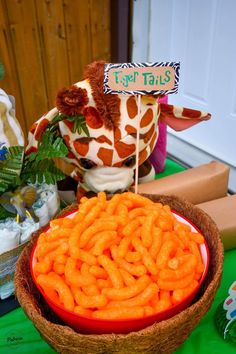 a giraffe head sitting on top of a wooden bowl filled with carrots