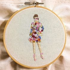 a woman with flowers in her dress is shown on a white background and has a cross stitch pattern