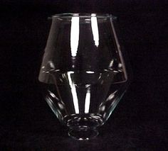 a clear glass vase sitting on top of a black tableclothed surface with light coming from the bottom