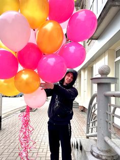 a person holding up many balloons in the air