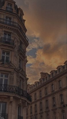 an old building with balconies and balconyes against a cloudy sky at sunset