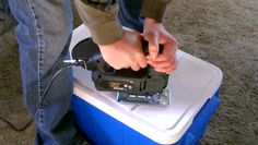 a person using a power tool on top of a blue and white box