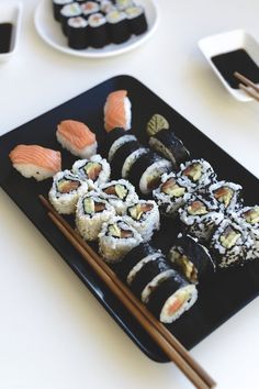 sushi on a black plate with chopsticks next to it