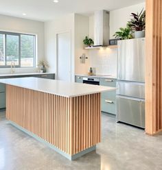 a large kitchen with an island in the middle and stainless steel appliances on both sides