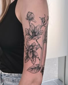 a woman with a tattoo on her arm holding a knife and flowers in the background