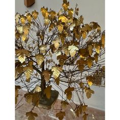 a small tree with gold leaves in a vase