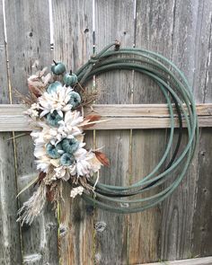 a wreath with flowers on top of a wooden fence