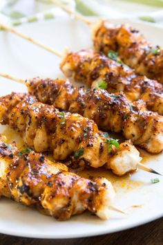 chicken skewers are sitting on a white plate