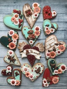 many decorated cookies are arranged in the shape of hearts and flowers on a wooden table