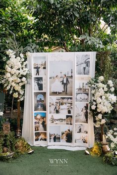 an outdoor ceremony with white flowers and photos on the wall, surrounded by greenery