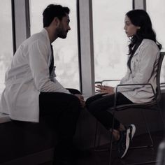 a man and woman sitting in chairs looking at each other