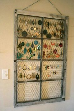 an old window is filled with earrings and earring hooks hanging on the wall next to a light switch