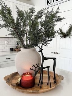 a white vase sitting on top of a counter next to a candle and some branches