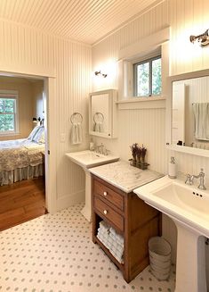 a bathroom with two sinks and a bed in the background