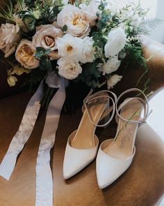 the bridal bouquet and wedding shoes are sitting on a chair with white flowers in it