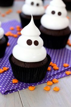 chocolate cupcakes with white frosting and sprinkles on a purple napkin