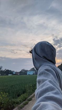 a person wearing a hoodie taking a selfie in front of a green field