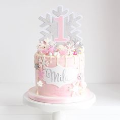 a pink cake with white frosting and flowers on top is decorated with a first birthday sign