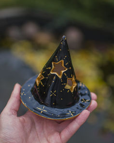 a hand holding a small black and gold party hat with stars on it's top