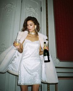 a woman in a white dress holding a wine bottle