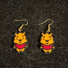 winnie the pooh beaded earrings are shown on a black surface, with yellow and red beads hanging from them