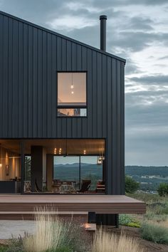 a black house with large windows and wooden deck