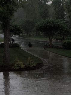 two people are walking down the street in the rain