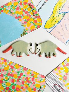 two plastic animals are sitting on top of some colorful papers and paper cuttings to make them look like they're kissing each other