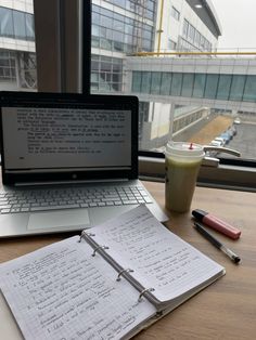 an open laptop computer sitting on top of a wooden desk next to a cup of coffee