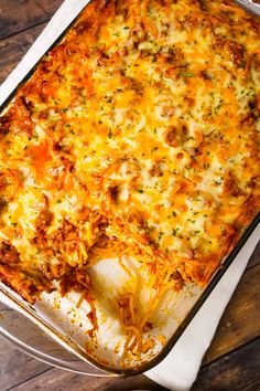 a casserole dish with meat and cheese in it sitting on a wooden table