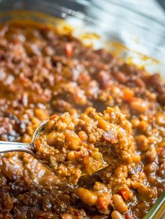 a spoon full of chili and beans in a casserole dish