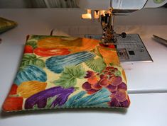 a close up of a sewing machine on a table with a flowered cloth next to it