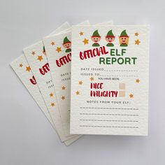 four elf report cards sitting next to each other on top of a white tablecloth