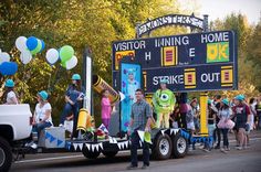 people standing on the back of a truck with monsters in front of it and balloons