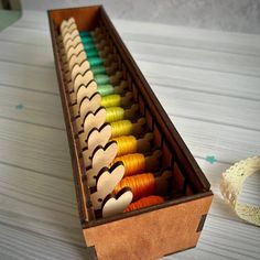 a wooden box filled with different colored thread spools