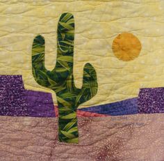 a quilted wall hanging with a cactus and sun in the sky on it's side