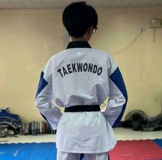 a young man standing on top of a blue and red mat wearing a white uniform