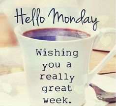 a coffee cup with the words hello monday written on it and a spoon next to it