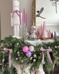 a mantle decorated with christmas decorations and pink candlesticks on top of the mantel