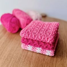 two crocheted pink and white towels sitting on top of a wooden table