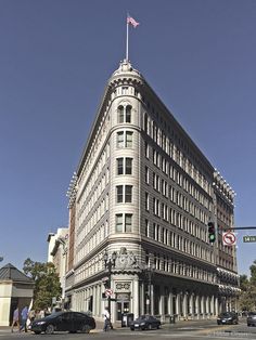 an old building on the corner of a street with cars parked in front of it