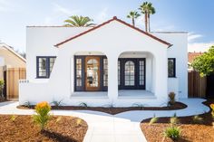 a white house with black shutters and palm trees