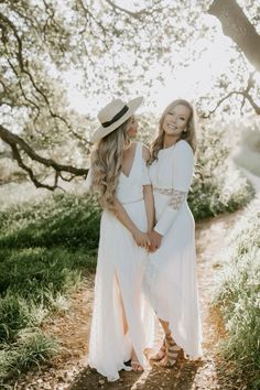 two women standing next to each other on a dirt road