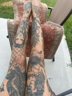 a person with tattoos on their legs sitting in a chair