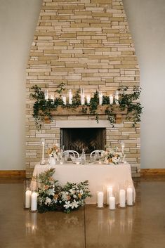 a table with candles and flowers is set up in front of a brick fire place