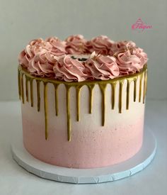 a pink and gold cake with icing drizzled on it's sides