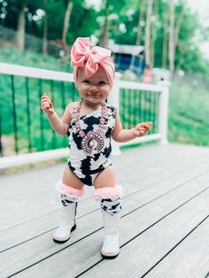 a baby girl in a black and white bodysuit with pink bows on her head