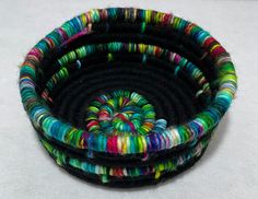 there are three different colored yarns in the basket on the table, and one is black with multicolored stripes