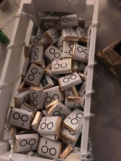 a box filled with lots of gold and white dices that have glasses on them