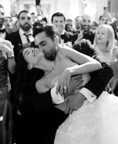 a bride and groom hugging each other in front of a crowd